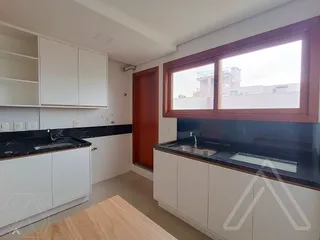 Foto da cozinha com armários brancos e bancadas escuras.