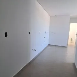 Vista interna de um corredor branco em um imóvel.