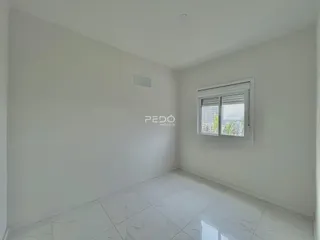 Ambiente interno de uma sala com piso de porcelanato claro e paredes brancas.