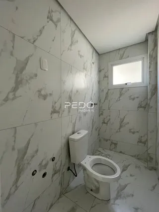 Foto de um banheiro com revestimento de mármore claro e vaso sanitário branco.