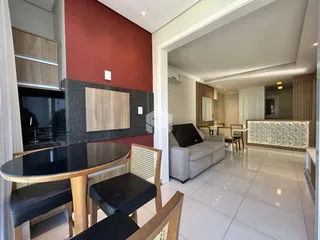 Sala de estar com mesa de jantar e parede vermelha em um imóvel no Brasil.