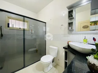 Banheiro com box de vidro e piso cerâmico.