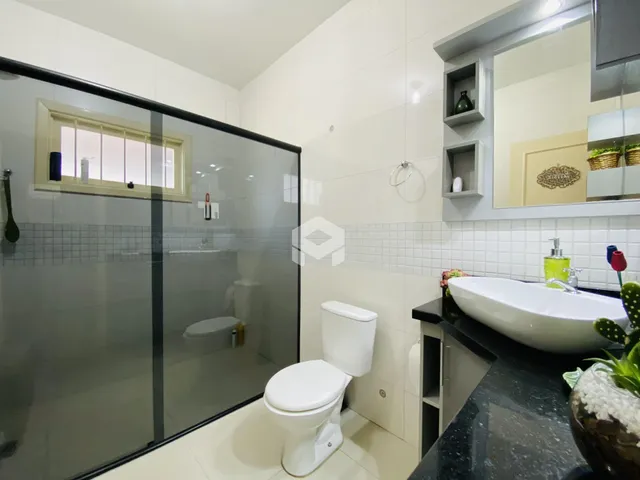 Banheiro com box de vidro e piso cerâmico.