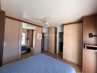Quarto com armários em madeira e cama no interior de uma residência.