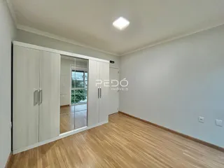 Ambiente interno de uma sala com piso de madeira e armários embutidos brancos.