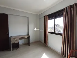 Ambiente interno de uma sala com piso de madeira e janela.