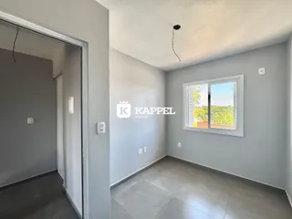 Uma sala ampla com piso de cerâmica e janela com vista para a vegetação externa.