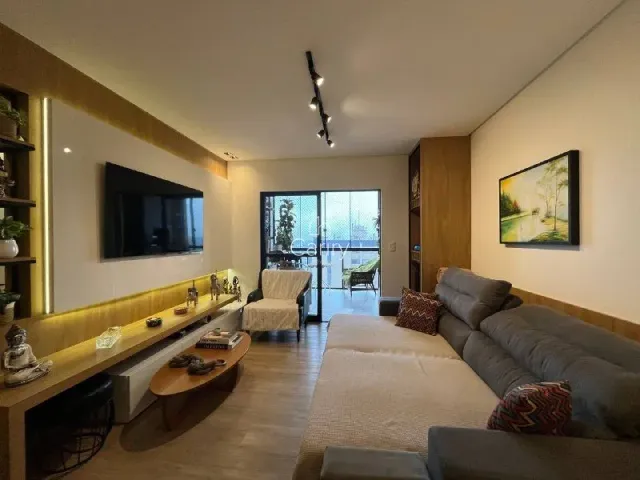 Sala de estar com sofá e televisão em um ambiente com piso de madeira.