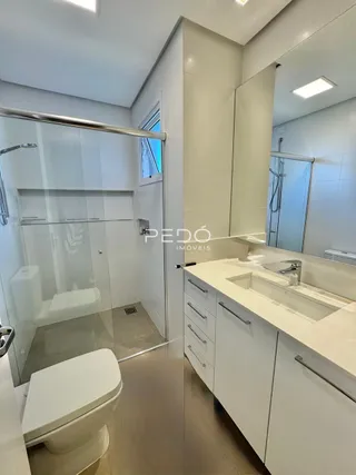 Foto de um banheiro moderno com box de vidro e louças brancas.