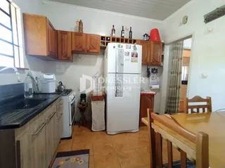 Interior de uma cozinha com armários de madeira e geladeira branca.