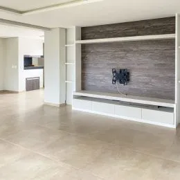 Vista interna de uma sala com painel de parede moderno e piso de cerâmica.