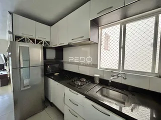 Foto de uma cozinha moderna com armários brancos e bancadas escuras.