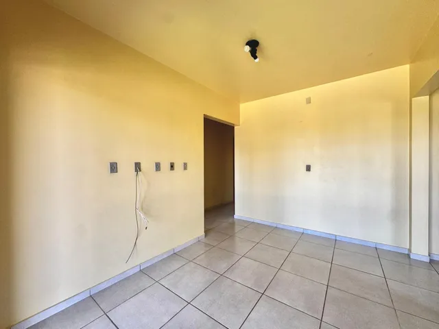 Corredor com paredes amarelas e piso de cerâmica.