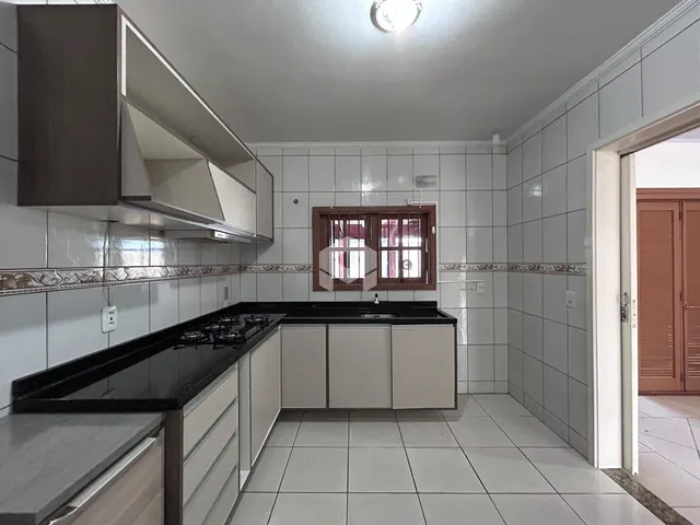 Foto de uma cozinha com armários brancos e piso cerâmico.