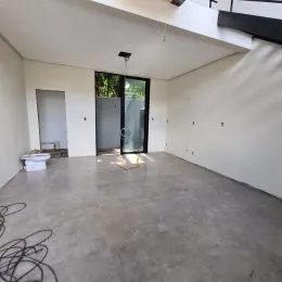 Foto de um ambiente interno amplo com piso de concreto e paredes brancas.