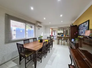 Sala de jantar com mesa de madeira e janela em um imóvel no Brasil.