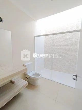 Banheiro com box de vidro e piso claro.