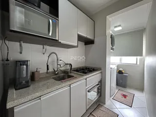 Cozinha com armários brancos e bancada de granito.
