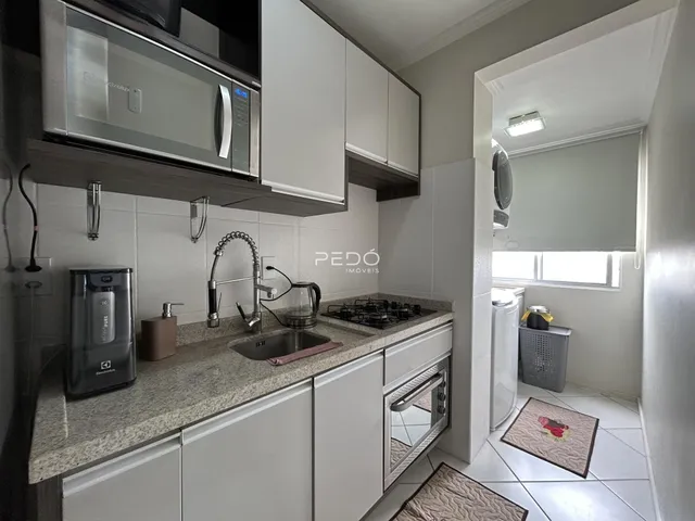 Cozinha com armários brancos e bancada de granito.