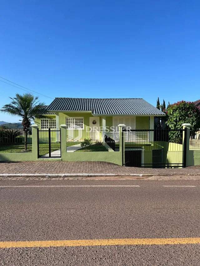 Fachada de uma casa em Lajeado, Brasil com cerca e muro verde.