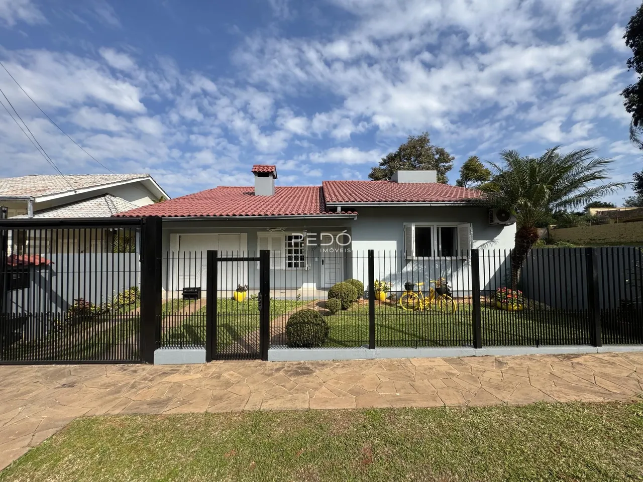 Fachada de uma casa em Lajeado, Brasil, com cerca e jardim na frente.