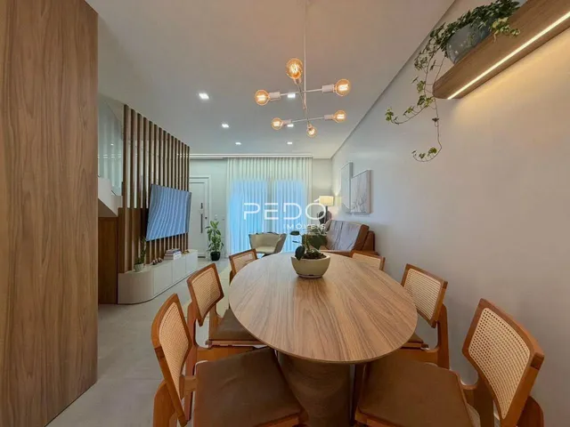 Uma sala de jantar com mesa de madeira e cadeiras em um ambiente claro.