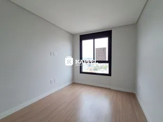 Uma sala de estar com piso de madeira clara e uma grande janela.