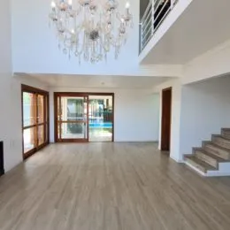Sala de estar ampla com piso de madeira clara.