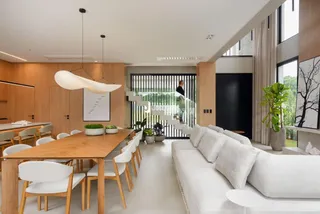 Interior de uma sala de estar e jantar com piso de madeira clara e móveis modernos.