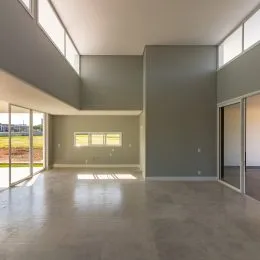 Foto de um espaço interno amplo com piso de concreto polido e paredes cinzas.