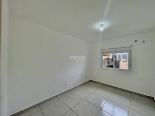 Ambiente interno de uma sala com piso de cerâmica e janela.