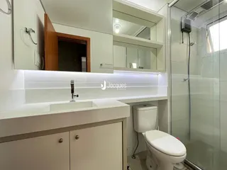 Foto de um banheiro moderno com box de vidro e louças brancas.