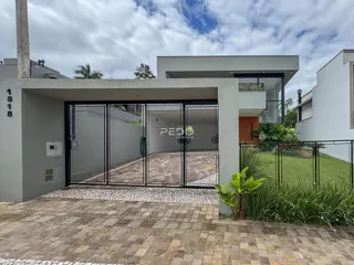Fachada moderna de uma residência em Lajeado, Brasil, com portão de ferro e paisagismo.