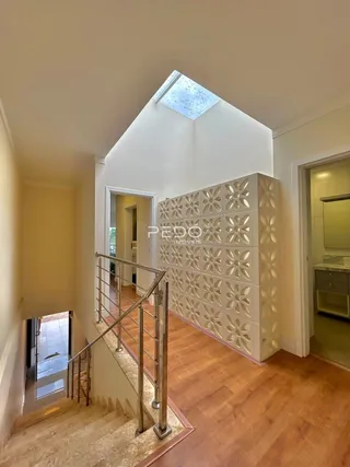 Hall com piso de madeira e corrimão de metal na residência.