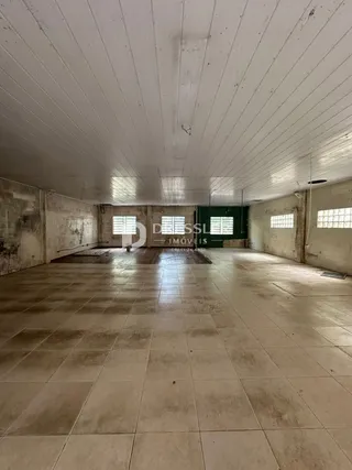 Interior de um espaço amplo com piso de cerâmica e paredes de concreto.