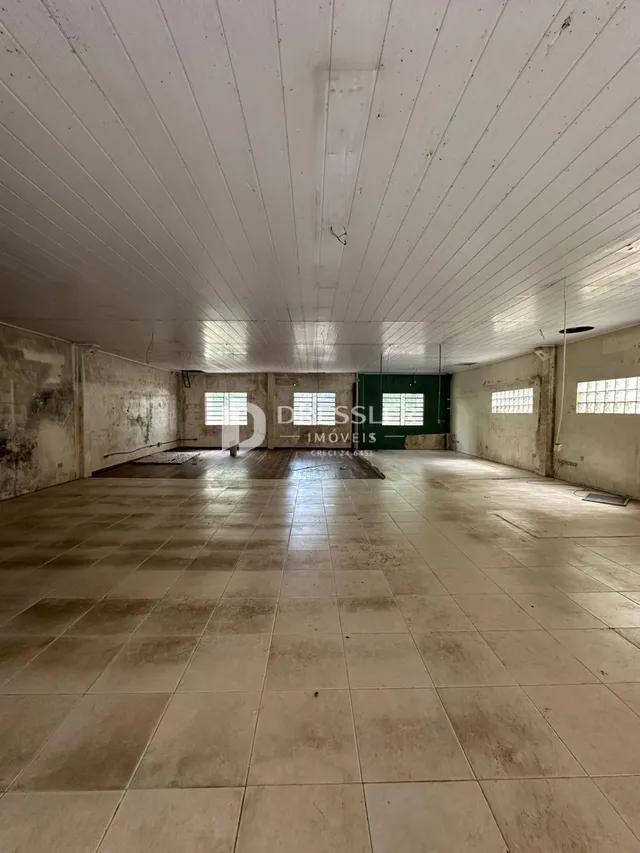 Interior de um espaço amplo com piso de cerâmica e paredes de concreto.