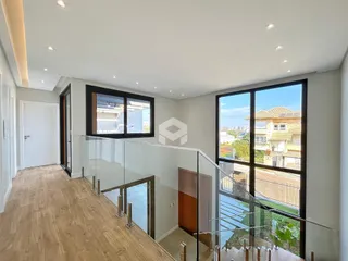 Hall de entrada com piso de madeira e parapeito de vidro.