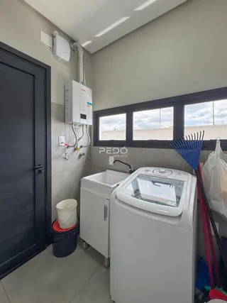 Vista interna de uma área de serviço com pia e máquina de lavar em um imóvel.