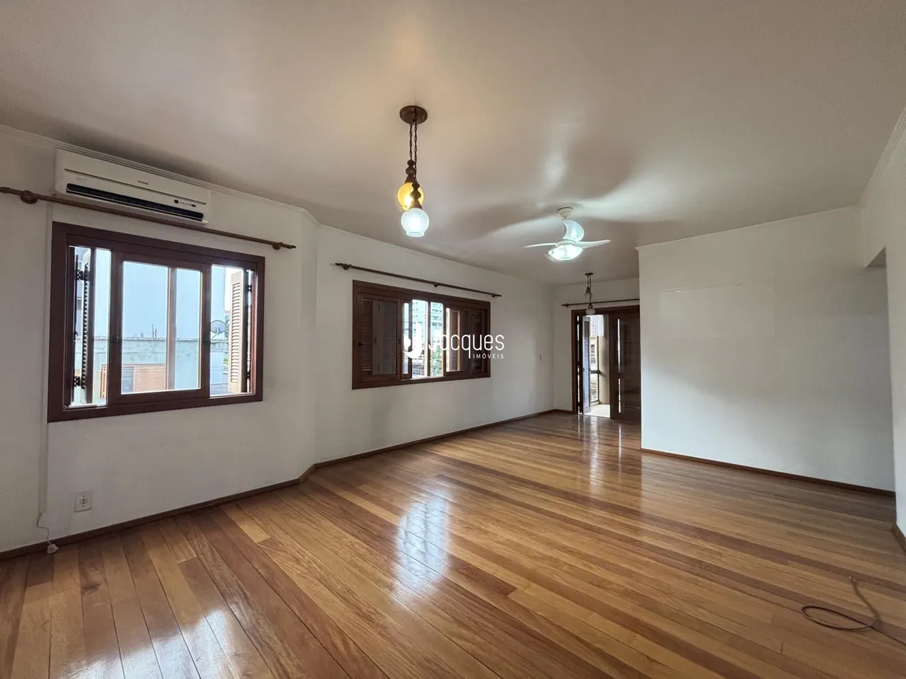 Sala de estar com piso de madeira polida e janelas.