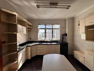 Foto de uma cozinha com armários brancos e janela para a paisagem urbana.