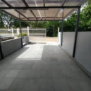 Pátio externo com estrutura de cobertura e cerca branca.