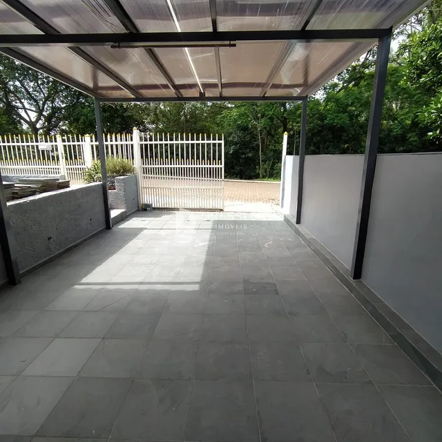 Pátio externo com estrutura de cobertura e cerca branca.