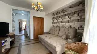 Sala de estar com sofá de couro e parede de destaque de tijolos na residência.