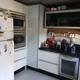 Cozinha com armários brancos e eletrodomésticos de aço inoxidável.