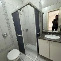 Foto de um banheiro com azulejos brancos e um box de vidro.