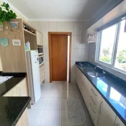 Uma foto interna de uma cozinha com armários e janela.