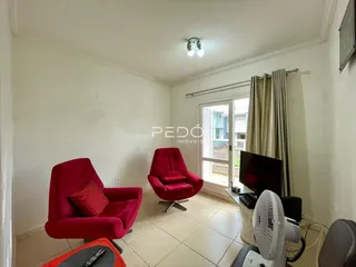 Sala de estar com duas poltronas vermelhas e porta de vidro.