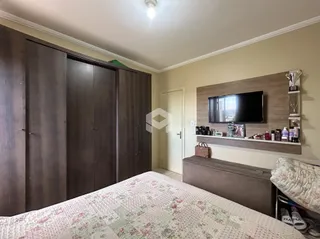 Quarto com armários de madeira e televisão na parede.