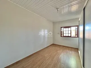 Ambiente interno de uma sala com piso de madeira clara e teto de painéis.