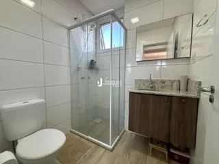 Banheiro com box de vidro e revestimento branco.